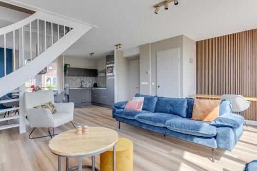 a living room with a blue couch and a table at Meerzicht 57 - 3 bedroom appt with sunny terrace in Uitgeest