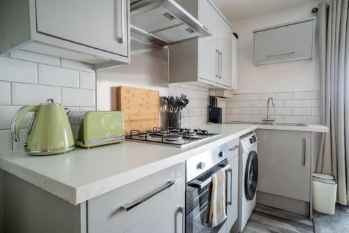 a white kitchen with a stove and a sink at The Station Inn Apartment in Yeadon