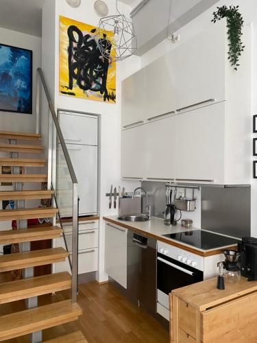 a kitchen with white cabinets and a staircase at Art Loft in downtown Oslo with Home Cinema in Oslo