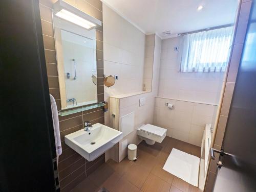 a bathroom with a sink and a toilet and a mirror at Nitro Rooms in Ljubljana