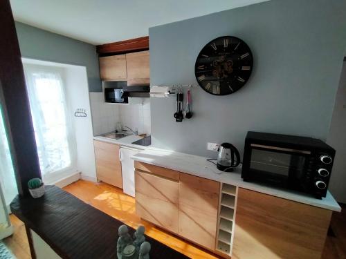 une cuisine avec un micro-ondes et une horloge au mur dans l'établissement Le 6 Magnifique Lafayette, à Bagnères-de-Bigorre