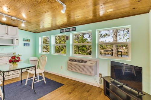 a living room with a table and a tv and some windows at Herron's Nest in Pensacola