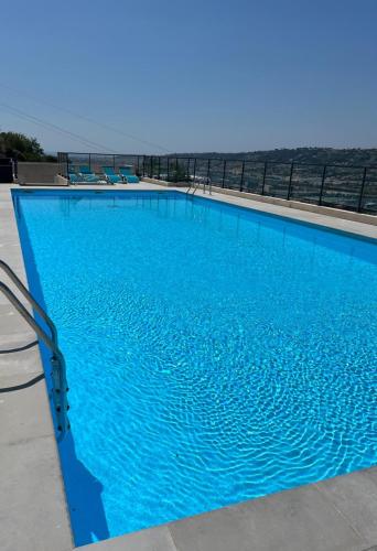 une grande piscine bleue avec l'océan en arrière-plan dans l'établissement Joli 3 pièces ensoleillé sur les hauteurs de Nice, à Nice