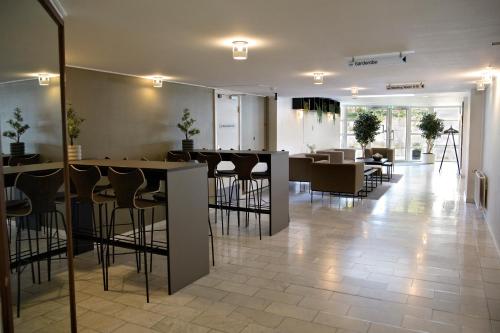 a restaurant with a bar with stools and tables at Golf Hotel Viborg in Viborg