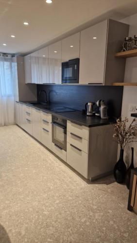 a kitchen with white cabinets and a black counter top at Moderne F3 - 10 min aeroport CDG - Paris - Parc Astérix - Disneyland Paris - Tour Eiffel - Champs Elysée - 15 min Parc des expositions Villepinte - 10 min Le Bourget - 5 min du Golf international de Roissy- JO 2024 in Le Thillay