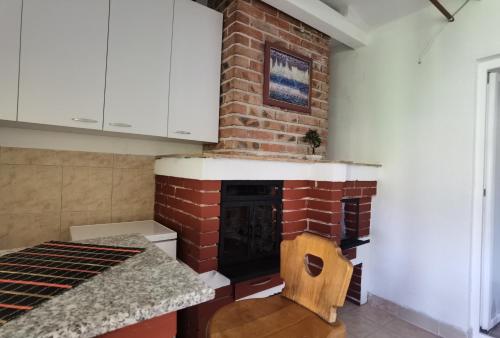 Una cocina con chimenea de ladrillo con una silla de madera. en Cele's Garden, en Ohrid