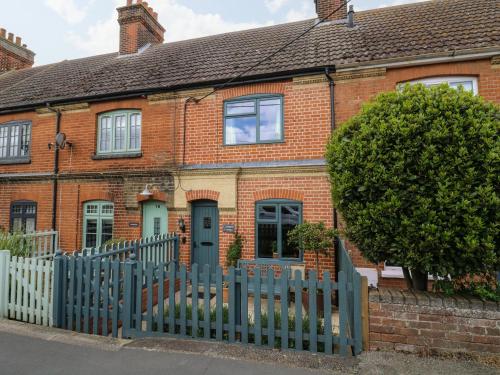 a brick house with a blue fence in front of it at Compass Cottage in Aldeburgh