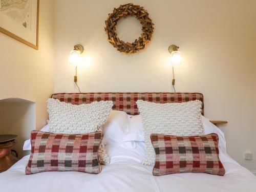 a bed with two pillows and a wreath on the wall at Compass Cottage in Aldeburgh