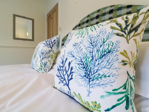 a bed with blue and white pillows on it at Compass Cottage in Aldeburgh