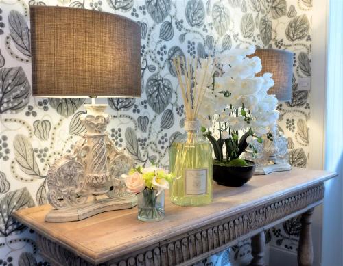 a table with a lamp and vases of flowers on it at Broomlands Farmhouse in Moffat
