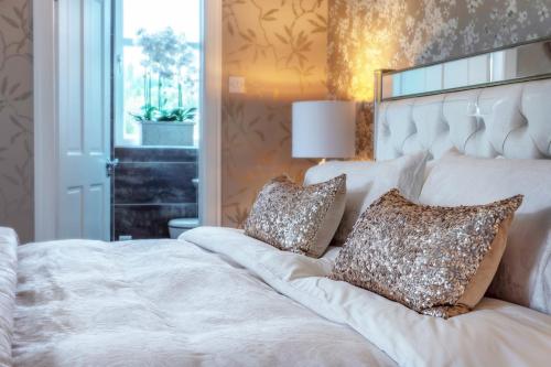 a bedroom with a large white bed with two pillows at Broomlands Farmhouse in Moffat