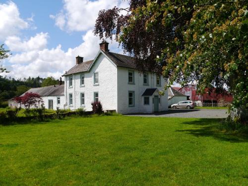 a white house with a car parked in front of it at Broomlands Farmhouse in Moffat
