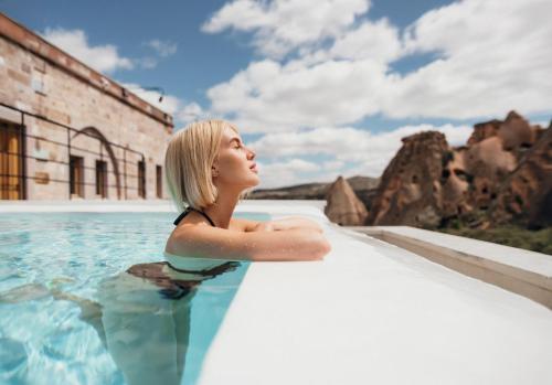 a woman in the water in a swimming pool at Millstone Cave Suites Hotel in Uchisar