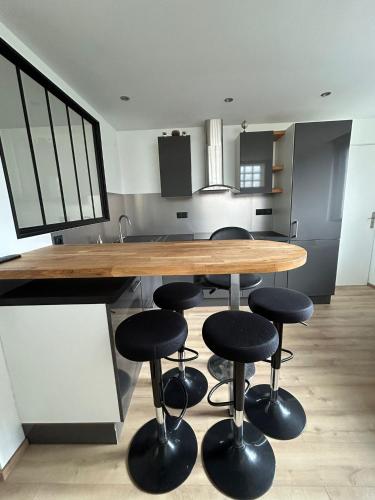 - une cuisine avec une table et des tabourets en bois dans l'établissement Studio CF Cosy Proche Gare, Centre Ville et Toutes Commodites, à Sainte-Savine