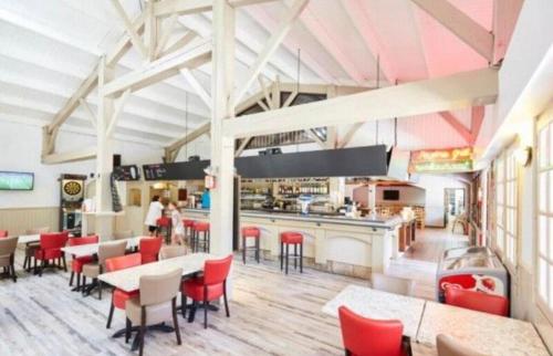 un restaurant avec des chaises et des tables rouges ainsi qu'un bar dans l'établissement Vacances de rêve au bord de mer, à Saint-Jean-de-Monts