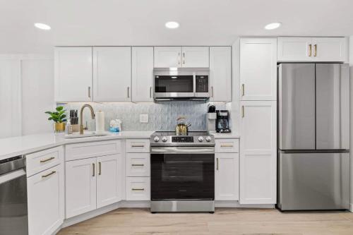 a kitchen with white cabinets and a stainless steel refrigerator at Luxury Ocean Front By Barefoot Landing in Myrtle Beach