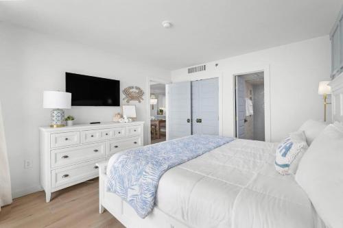 a white bedroom with a white bed and a tv at Luxury Ocean Front By Barefoot Landing in Myrtle Beach