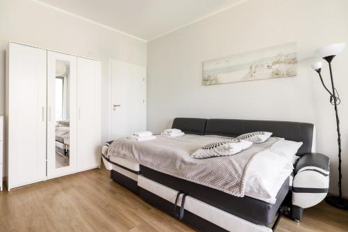 a white bedroom with a bed and a mirror at Baltic Apartments in Pobierowo