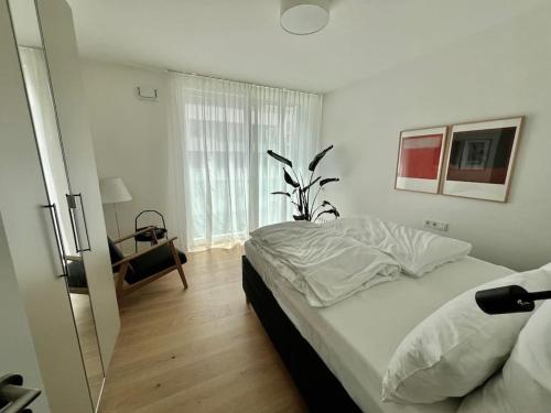a white bedroom with a bed and a window at Schickes 2-Zi-Apartment am Neckarufer im BUGA-Park in Heilbronn