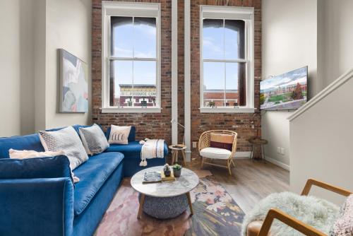 a living room with a blue couch and a brick wall at Trendy 3 bedroom Loft in Chinatown with Parking! in Victoria