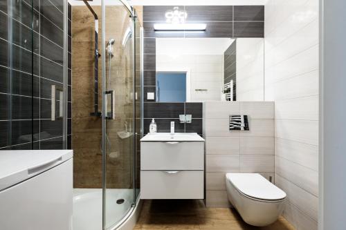 a bathroom with a toilet sink and a shower at Baltic Apartments in Pobierowo