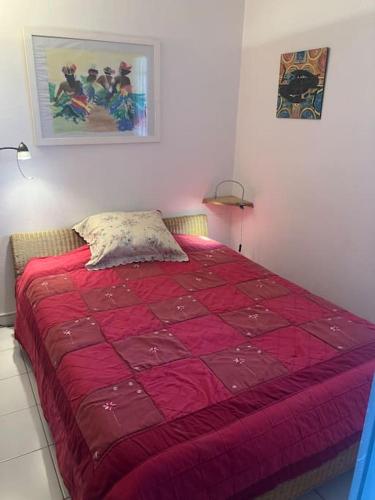 - une chambre avec une couette rouge sur un lit dans l'établissement VIAS PLAGE - Apt climatisé pour 4 personnes piscine collective, à Vias