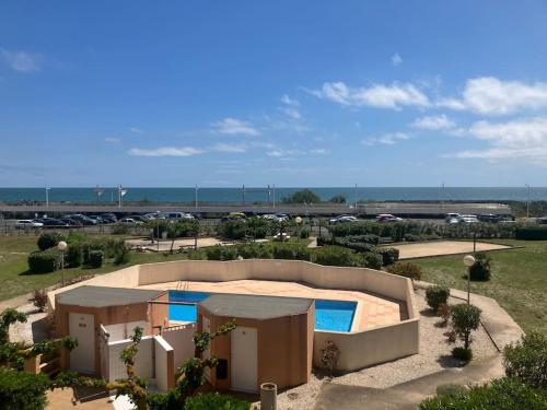 - un bâtiment avec une piscine à côté d'un parking dans l'établissement VIAS PLAGE - Apt climatisé pour 4 personnes piscine collective, à Vias