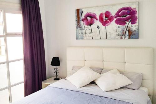 1 dormitorio con 1 cama blanca con flores rosas en Precioso apartamento con piscina y vista al mar en San Miguel de Abona