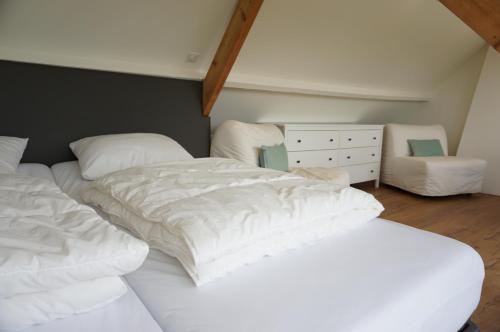 1 dormitorio con 2 camas con sábanas blancas y silla en Kustverhuur, 't Uusje Nieuwvliet, en Nieuwvliet