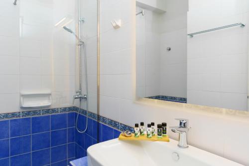 W łazience znajduje się umywalka i lustro. w obiekcie Paradise Art Hotel w mieście Andros