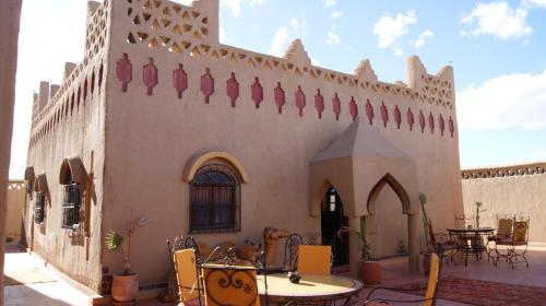 a building with a patio with tables and chairs at Riad Moha in Merzouga