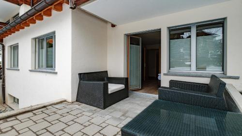 a patio with two chairs and a couch and windows at Casa Della Luce Apartments by Zermatt Premium Apartments in Zermatt