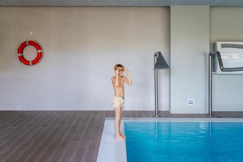 a young boy standing on the edge of a swimming pool at Amberton Green Apartments Palanga in Palanga