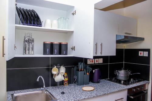 a kitchen with white cabinets and a sink and a counter top at Comfort & Style 1Bed Apartment, Luxore, Syokimau in Nairobi