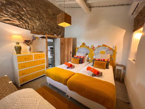 a bedroom with a large bed with yellow and orange sheets at Monte Refúgio do Silêncio in Portalegre