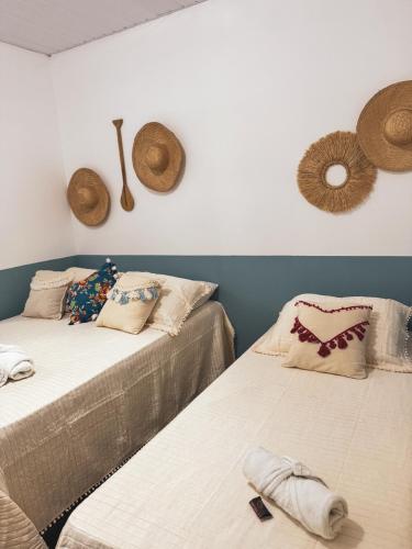 Carimbó Pousada e Hostel في ألتر دو تشاو: سريرين في غرفة مع قبعات على الحائط