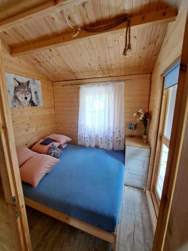 a bedroom with a blue bed in a wooden cabin at Leśny zakątek malediwy Jacuzzi free in Jaworzno
