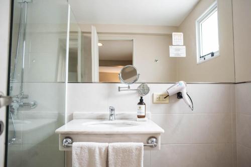 ein Bad mit einem Waschbecken und einer Dusche mit einem Spiegel in der Unterkunft DonSuites in Corrientes
