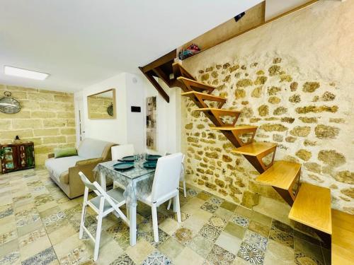un salon avec une table et un mur en pierre dans l'établissement La Peiro Malo - Charmant Duplex Centre Historique-CLIM-4 personnes, à Istres