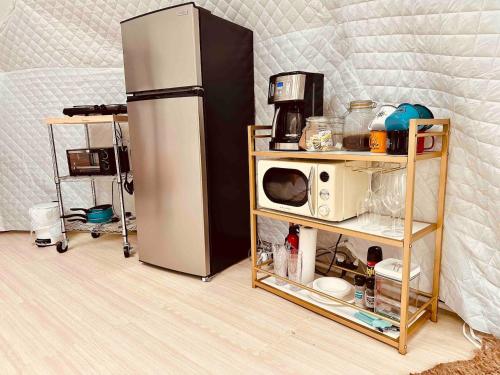 a refrigerator next to a shelf with a microwave at The Perch Glamping By Rafting in Cosby