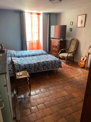 - une chambre avec un lit, une télévision et une chaise dans l'établissement Maison de l horloge, à Avallon