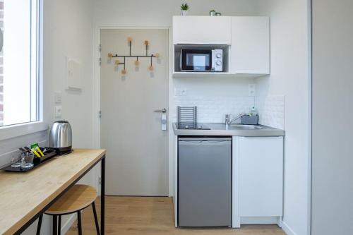 une cuisine blanche avec un évier et un comptoir dans l'établissement Appartement 4 proche de la gare et du centre ville, à Amiens