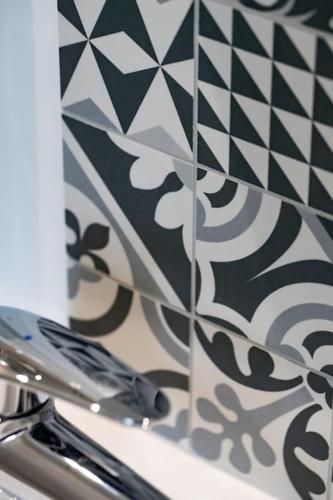La salle de bains est pourvue d'un mur carrelé noir et blanc. dans l'établissement Appartement 4 proche de la gare et du centre ville, à Amiens