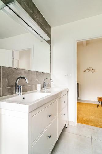 une salle de bain blanche avec un lavabo et un miroir dans l'établissement Appartement Séjour Confort, Clim, Piscine, à Ormoy-la-Rivière