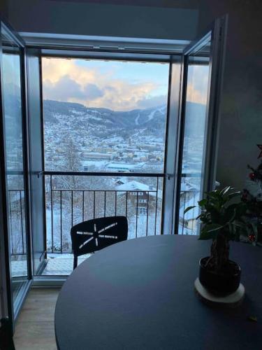 a table with a potted plant in front of a large window at appartement la fleur d'abeille avec une belle vue et spa in Gérardmer
