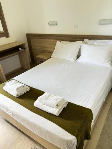 a large white bed with two towels on it at Armonia Apartments & Studios in Perivolion