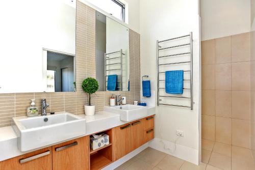 a bathroom with two sinks and a mirror at Riversea Goolwa Beach House in Goolwa