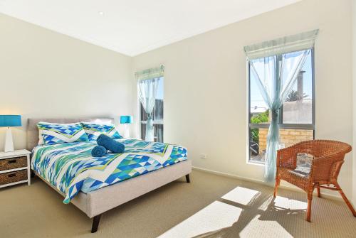 a bedroom with a bed and a chair and a window at Riversea Goolwa Beach House in Goolwa