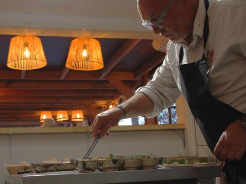 a man standing in a kitchen preparing food at Bella Vista Hôtel, Suites & Maisons in Porticcio