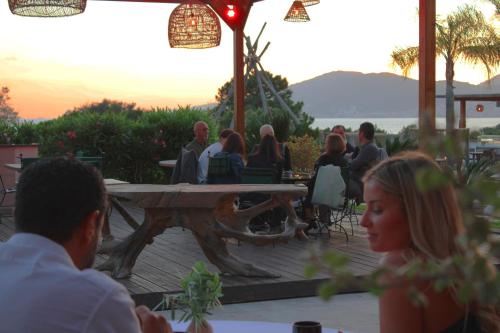 a group of people sitting around a picnic table at Bella Vista Hôtel, Suites & Maisons in Porticcio